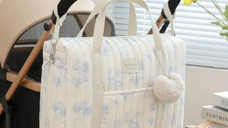 Bolsa de bebê acolchoada off-white com estampa floral azul pendurada no guidão de um carrinho de bebê