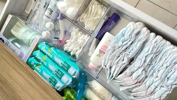 Gaveta organizada com cestos contendo fraldas, lenços umedecidos, cotonetes, algodão e itens de higiene do bebê