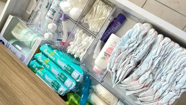 Gaveta organizada com cestos contendo fraldas, lenços umedecidos, cotonetes, algodão e itens de higiene do bebê