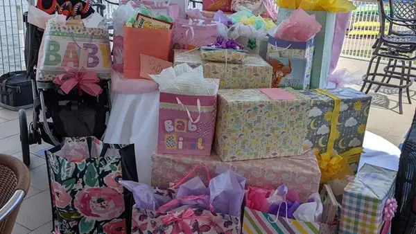 Mesa cheia de sacolas e caixas de presentes de chá de bebê com papéis decorados e laços coloridos